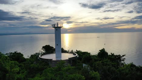 A-lighthouse-sits-in-the-top-of-a-mountain-near-the-ocean-where-it-is-properly-placed-and-has-a-stunning-view-of-the-sea-during-sunset