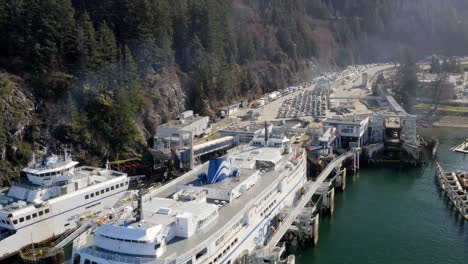 Transbordador-Atracado-En-El-Muelle-Mientras-Los-Vehículos-De-Pasajeros-Esperan-Para-Embarcar-En-La-Terminal-De-La-Bahía-De-Herradura-Por-Aguas-Verde-Esmeralda-En-Columbia-Británica,-Oeste-De-Vancouver,-Canadá