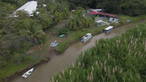 Man-standing-between-kayaks-and-boats-at-the-shore-of-rio-cotos-near-Manuel-Antonio,-Costa-Rica