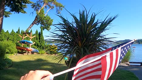 American-flag-with-stars-and-stripes-flies-in-wind-in-the-garden-on-the-beach-slow-motion-right-justified,-4th-of-July