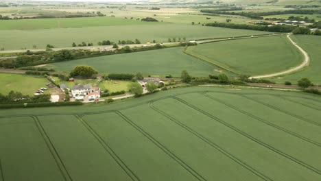 aerial-orbit-of-rural-farming-crop-fields-with-house-and-country-lanes