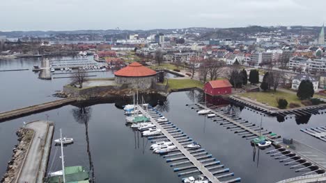 Christianholm-marina-and-Kristiansand-fortress-in-city-center---Forward-moving-ascending-aerial-from-marina-to-revealing-full-city-view-west-towards-Hannevika---Norway
