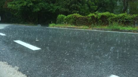 drops-of-water-fall-and-bounce-off-the-asphalt-of-a-country-road-during-a-heavy-summer-rain