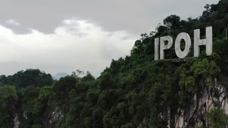 Drone-Vuela-Alrededor-De-La-Montaña-De-Piedra-Caliza-Con-Señalización-Ipoh-En-La-Cima-De-La-Colina,-La-Ciudad-Capital-De-Perak,-Malasia,-Sudeste-De-Asia