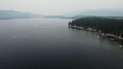Counterclockwise-drone-shot-of-the-shore-and-water-at-Lake-Payette-in-McCall,-Idaho-on-a-very-smoky-summer-day