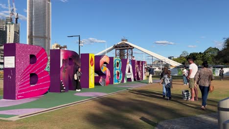 Iconic-touristic-landmark,-colorful-giant-block-letter-of-Brisbane-City-with-cross-river-bridge-construction-in-the-background-on-a-sunny-day,-Queensland-the-sunshine-state,-Australia