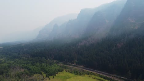 Drone-shot-of-towering-mountains-masked-by-smoke-and-contrasted-by-greenery-in-the-Columbia-River-Gorge