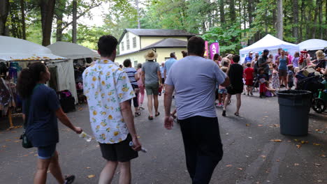 A-Group-of-Tourists-walk-by-vendor-tents-at-an-art-show-in-the-woods