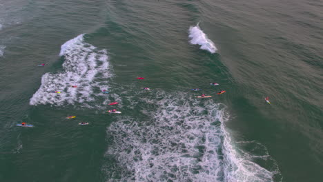 Aerial-view-looking-down-at-a-group-of-Nippers-on-boards-paddling-out-in-the-ocean-during-a-morning-training-session-with-water-safety-at-the-popular-Mermaid-Beach-Gold-Coast-QLD-Australia