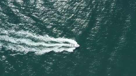 top-down-follow-drone-shot-of-small-speed-boat-in-a-blue-sea