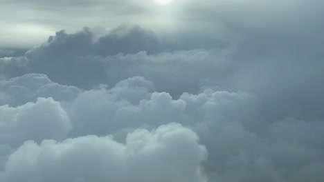 PILOT-VIEW,-BACKLIT---Descending-towards-stormy-cumulonimbus-clouds,-commercial-flight