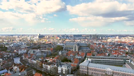 Aerial-shot-flying-up-over-the-ancient-city-of-Leiden,-revealing-the-Faculty-of-Law-of-Leiden-University,-the-Pieterskerk-and-the-Rapenburg-canal
