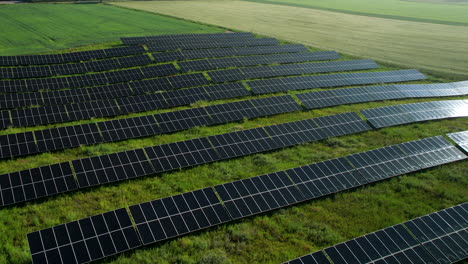 Aerial-flyover-solar-panel-farm-on-grass-field-during-sunlight-in-countryside,4K