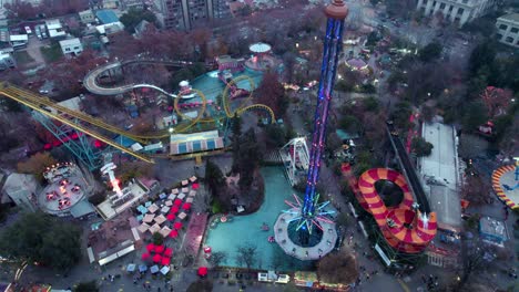 Aerial-rising-over-Fantasilandia-amusement-park-rollercoasters,-rides-and-extreme-games-in-O'Higgins-Park,-Santiago,-Chile
