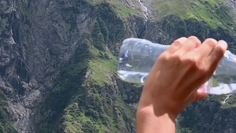 a-teenager-drinks-a-bottle-of-water-in-the-Alps-to-dehydrate-during-a-hike-in-the-mountains-,-Switzerland,-Obwalden