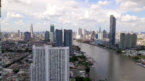 Paisaje-Urbano-De-Rascacielos-De-Bangkok-Por-El-Río-Chao-Phraya,-Tiro-Lateral-Aéreo,-Tailandia