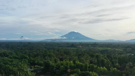 Amanecer-Temprano-En-La-Mañana-Con-Vistas-A-La-Selva-Tropical-En-Ubud-Bali-Con-Volcán-En-El-Horizonte,-Aéreo