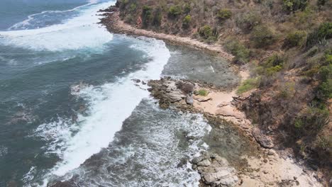 Drone-flying-over-a-rocky-island-of-Ixtapa-located-in-the-state-of-Guerrero,-Mexico-during-a-sunny-day