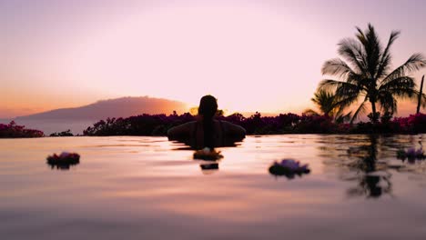 Junge-Tätowierte-Hawaiianische-Frau-Beobachtet-Den-Sonnenuntergang-Hinter-Einer-Insel-Von-Einem-Infinity-Pool-Aus