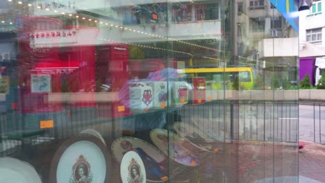Pedestrians-are-seen-reflected-on-a-gift-and-ornament-shop-window-selling-Britain-colonials,-such-as-the-royal-family-and-specifically-Queen-Elizabeth-II,-theme-products-in-Hong-Kong