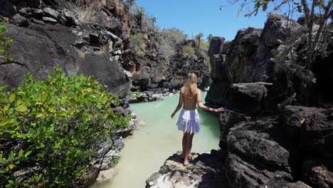 Female-Tourist-Walking-Down-Rock-Steps-To-View-Natural-Pool-At-Las-Grietas-In-Santa-Cruz-Island,-Galapagos