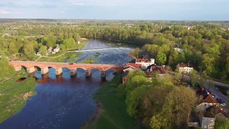 Luftaufnahme,-Die-Auf-Die-Alte-Backsteinbrücke-über-Den-Fluss-Venta-In-Kuldiga,-Lettland,-Zufliegt