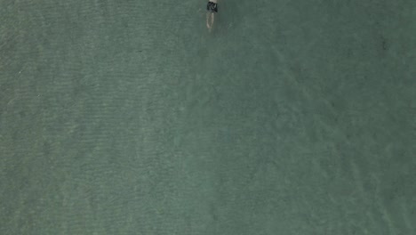 Drone-shot-of-man-swimming-in-crystal-blue-water