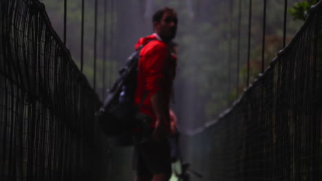 Joven-Explorador-Masculino-Caminando-Sobre-Un-Puente-Colgante-En-Un-Sendero-De-Trekking-En-La-Selva-Tropical-Explorando-La-Selva-Centroamericana-En-Costa-Rica