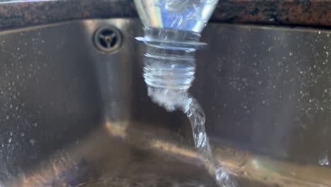 Close-up-shot-of-pouring-fresh-water-from-bottle-into-kitchen-sink