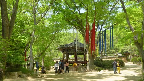 People-walking-near-Seonangdang,-which-is-a-shrine-that-acts-like-the-guardian-of-the-village-at-Korean-Folk-Village-In-Yongin-Of-Gyeonggi-In-South-Korea