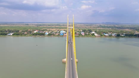 Aerial-flyover-Neak-Loeung-Bridge-with-driving-cars-crossing-calm-Mekong-River-during-sunny-day