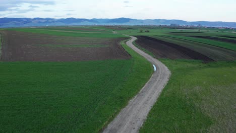 Long-And-Winding-Dirt-Road-Through-Vast-Meadow-Landscape