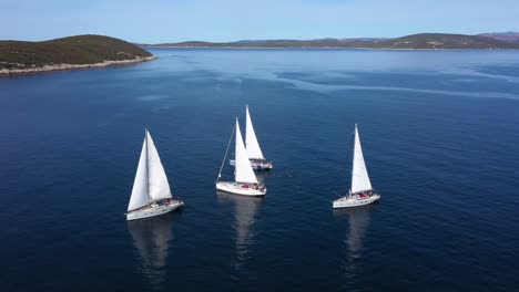 Tourists-Swimming-On-A-Calm-Blue-Sea-Beside-White-Sailboats-In-Hvar,-Croatia