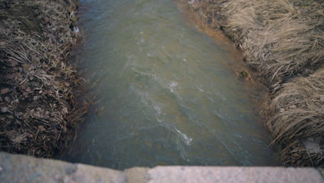 Langsamer-Push-In-Schuss-Von-Oben-Auf-Wasser,-Das-Aus-Dem-Abwasserkanal-Im-Freien-Fließt