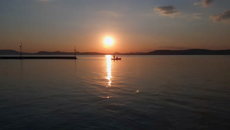 Kleines-Boot,-Das-Während-Des-Wunderschönen-Sonnenuntergangs-Silhouettiert-Wurde,-Bewegt-Sich-Langsam-Im-Ruhigen-Hafen