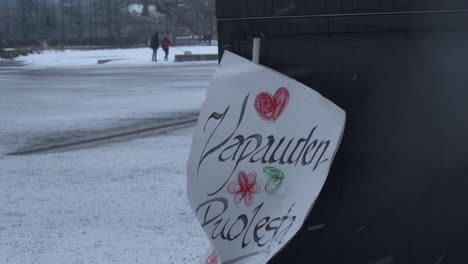 Closeup-shot-of-a-sigh-pinned-up-in-Helsinki-saying-For-the-freedom-during-the-Covid-19-protests,-cold-snowy-day