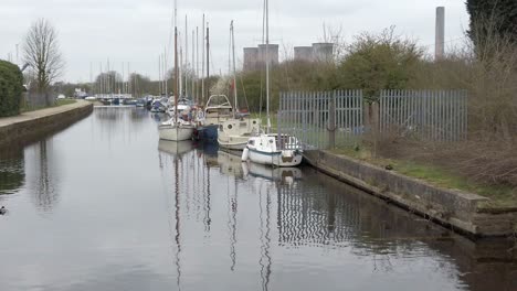 Small-sailboats-moored-on-narrow-rural-countryside-canal-marina