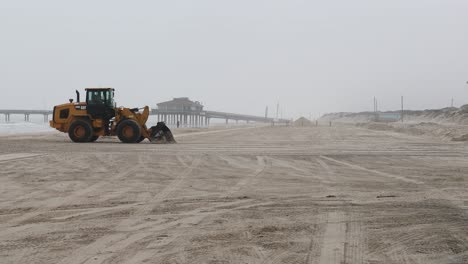 Caterpillar-930M-wheel-loader-using-the-bucket-to-level-the-sand-on-White-Cap-Beach-on-North-Padre-Island-on-a-foggy-morning