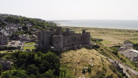 Harlech-castle-in-North-Wales,-Gwynedd,-UK,-shot-by-drone-to-show-proximity-of-the-castle-against-the-town-and-coast