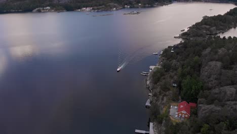 Drone-view-of-boat-leisurely-cruising-along-coastline-of-Kragerofjorden,-Norway