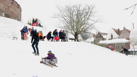 Children-and-parents-sledding-on-a-snowy-Burcht-in-Leiden,-the-Netherlands-during-the-pandemic