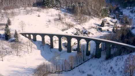 Steinbahnviadukt-über-Einem-Kleinen-Dorf-Im-Winter,-Verschneite-Landschaft