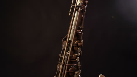Nach-Oben-Und-Unten-Geneigte-Aufnahme-Eines-Vintage-Saxophons-Auf-Einem-Ständer,-Dunkler-Hintergrund