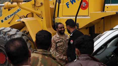 Soldado-Paquistaní-Bajando-En-Una-Excavadora-Y-Luego-Felicitando-A-Un-Policía-Por-Despejar-La-Carretera-Debido-A-Un-Deslizamiento-De-Tierra-En-La-Autopista-Karakoram-En-Pakistán