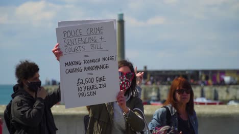 close-up-on-a-card-of-a-woman-from-protest-group-by-the-seaside-is-holding-card-about-police-crime-sentencing-and-court-bills-which-are-being-discussed-to-take-place,-stand-for-your-rights