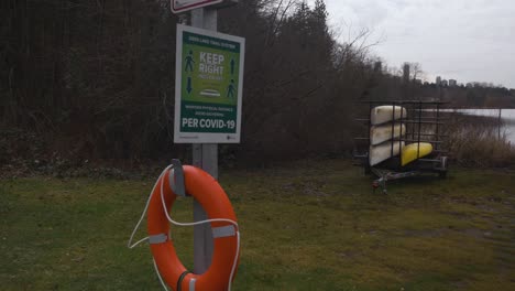 Life-buoy-hanging-on-a-post-under-a-COVID-19-recommendation-sign-suggesting-2-metres-of-social-distancing-at-Deer-lake-park-Canoe-Rental-area