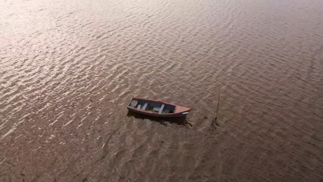 4K-aerial-view-of-an-old-fishing-boat-anchored-in-the-middle-of-the-Ria-de-Aveiro,-estuary-of-river-Vouga,-drone-steady-over-the-boat,-60fps