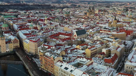 Vista-Aérea-Cinematográfica,-Casco-Antiguo-De-Praga-En-Invierno,-Nieve-En-Los-Edificios-De-La-Ciudad-En-La-Tarde-Fría,-Tráfico-Por-El-Río-Vltava,-República-Checa,-Tiro-Con-Drones