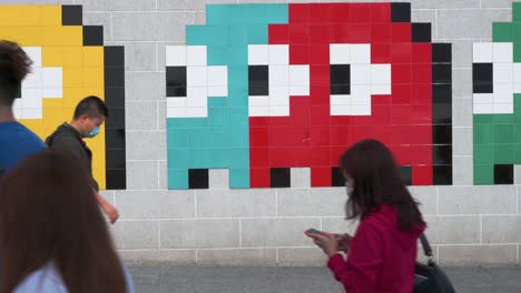 Man-Sieht-Fußgänger-An-Einem-Wall-Street-Kunstwerk-Vorbeigehen,-Das-Das-Klassische-Arcade-Spiel-Pac-Man-In-Hongkong-Darstellt