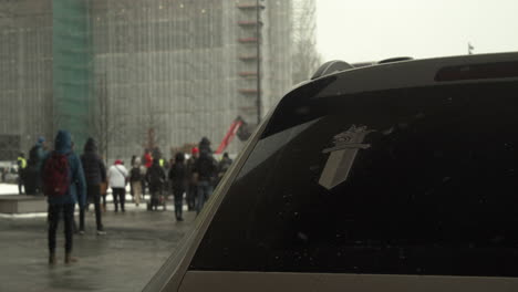 Wide-shot-of-a-police-car-with-a-police-of-Finland-logo-in-the-window,-protester-in-the-background